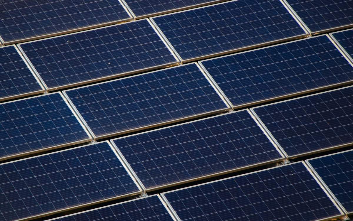 Muitas fileiras de painéis solares na cobertura de um prédio comercial.